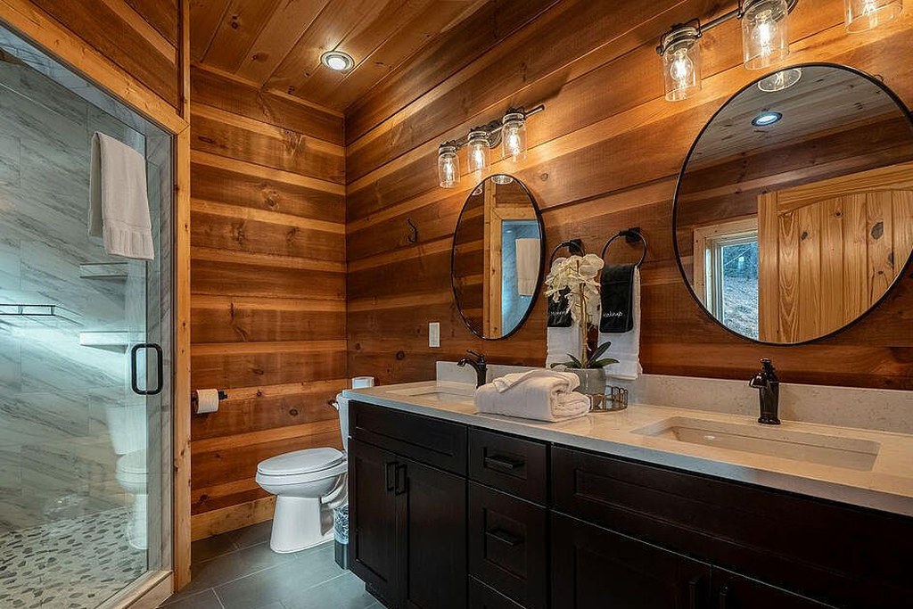 Ensuite vanity with round mirrors and tile shower beyond