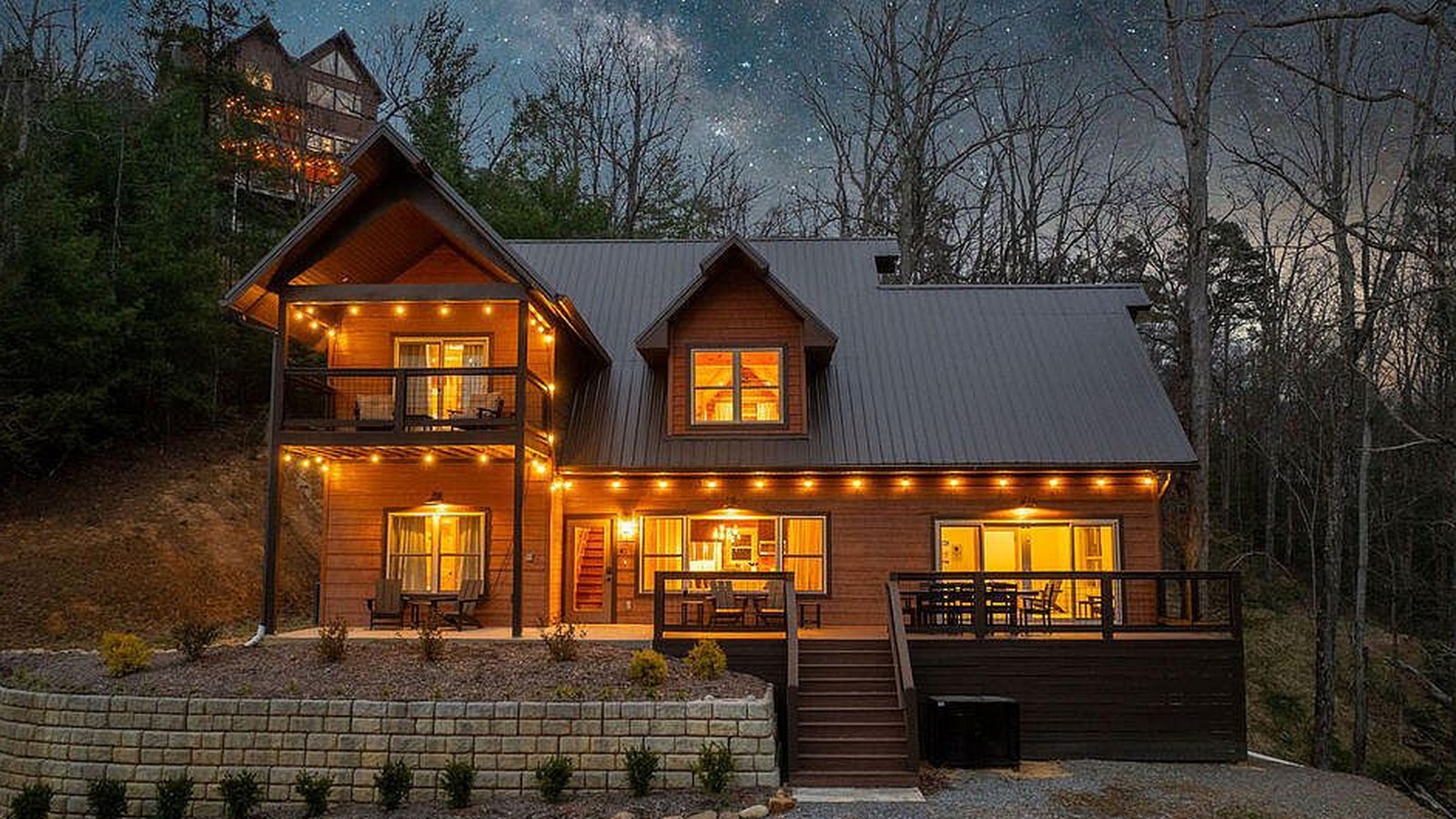 Dusk elevation of the log home at 4228 Wears Valley Road, exterior and interior lights on