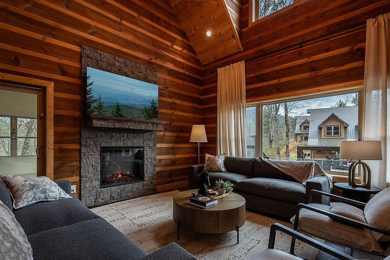 Great room with deep sectional anchored to the hearth wall under exposed trusses