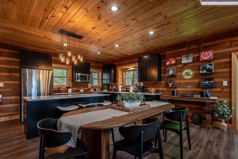 Long plank dining table for eight with a linear blackened metal fixture above