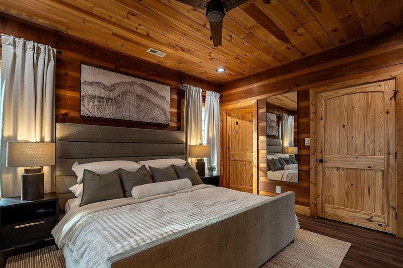 Primary bedroom with upholstered bed, layered linens and flanking lamps