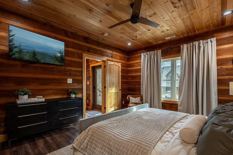 Second bedroom with quilted coverlet and black nightstands against log wall