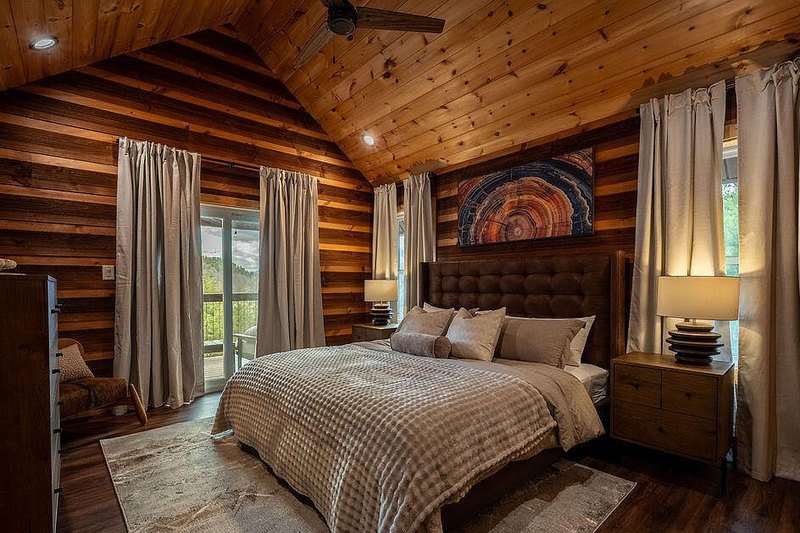 Third bedroom with tufted headboard, layered throws and blackout curtains