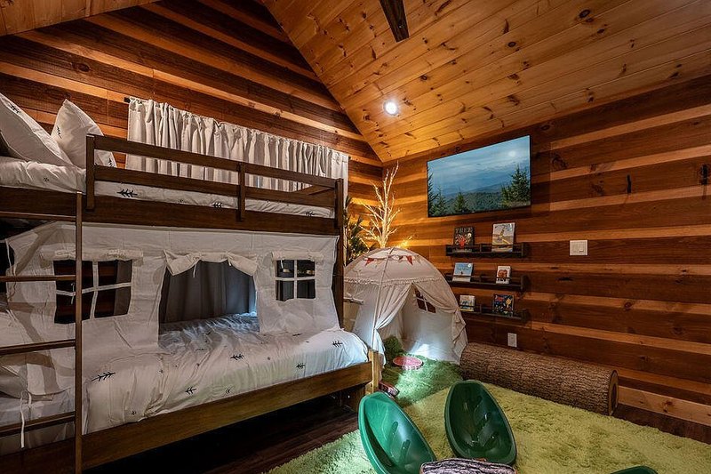 Bunk room with built-in bunks, canopy styling and a green floor rug