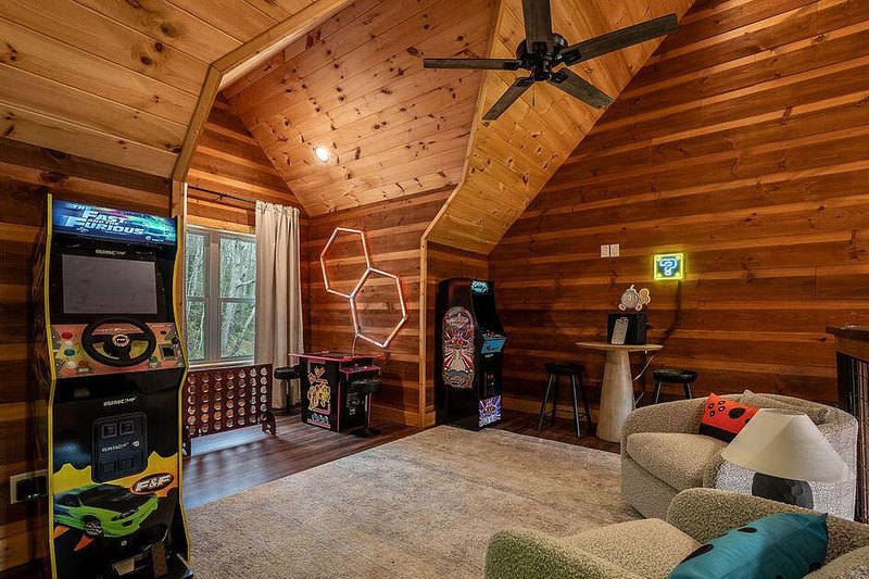 Loft game room with arcade cabinets and a seating cluster, loft rail kept clear
